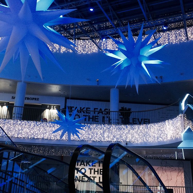 Store stjerne med blåt lys hænger ned fra loftet til BRuuns Galleris juleudstilling