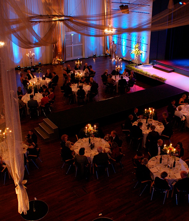 Til galla temafest er der hængt store løbere af stof i loftet og på væggene, store lysekroner står på de hvide borde, masser af stearinlys er fordelt og en stor scene er i front