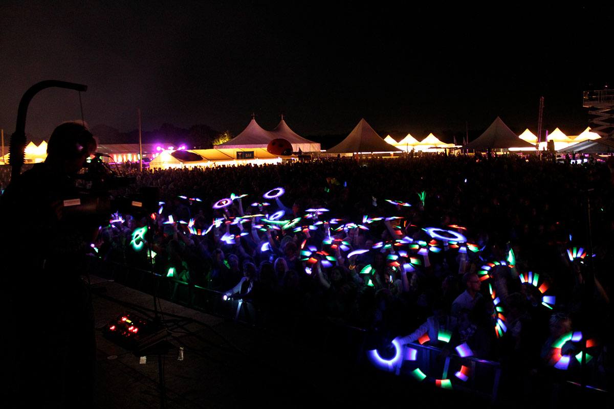 Tilskuere med neonlyssmykker foran scenen til Rodkjærs festivalevent