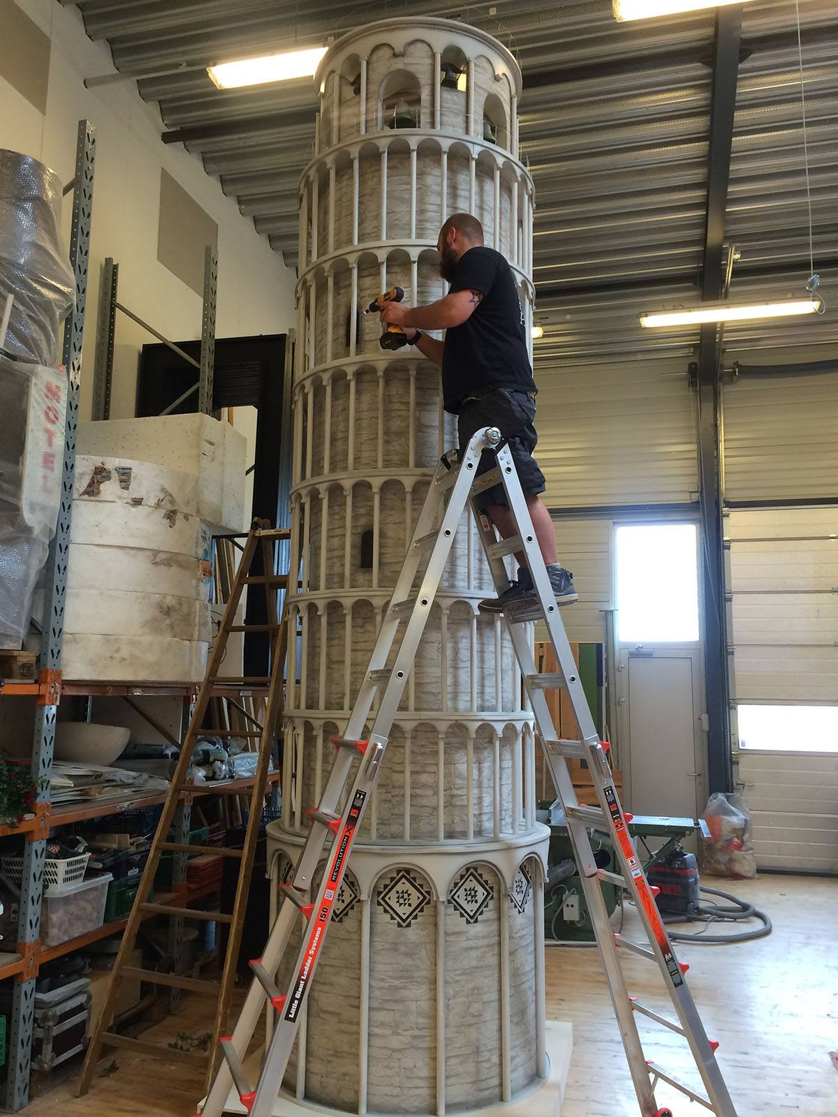 Rodkjær medarbejder står på en høj stige for at kunne færdigegøre den høje model af det skæve tårn i Pisa
