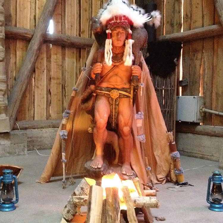 Stor, specialfremstillet indianerhøvding der står foran det lille bålsted med lanterner omkring 