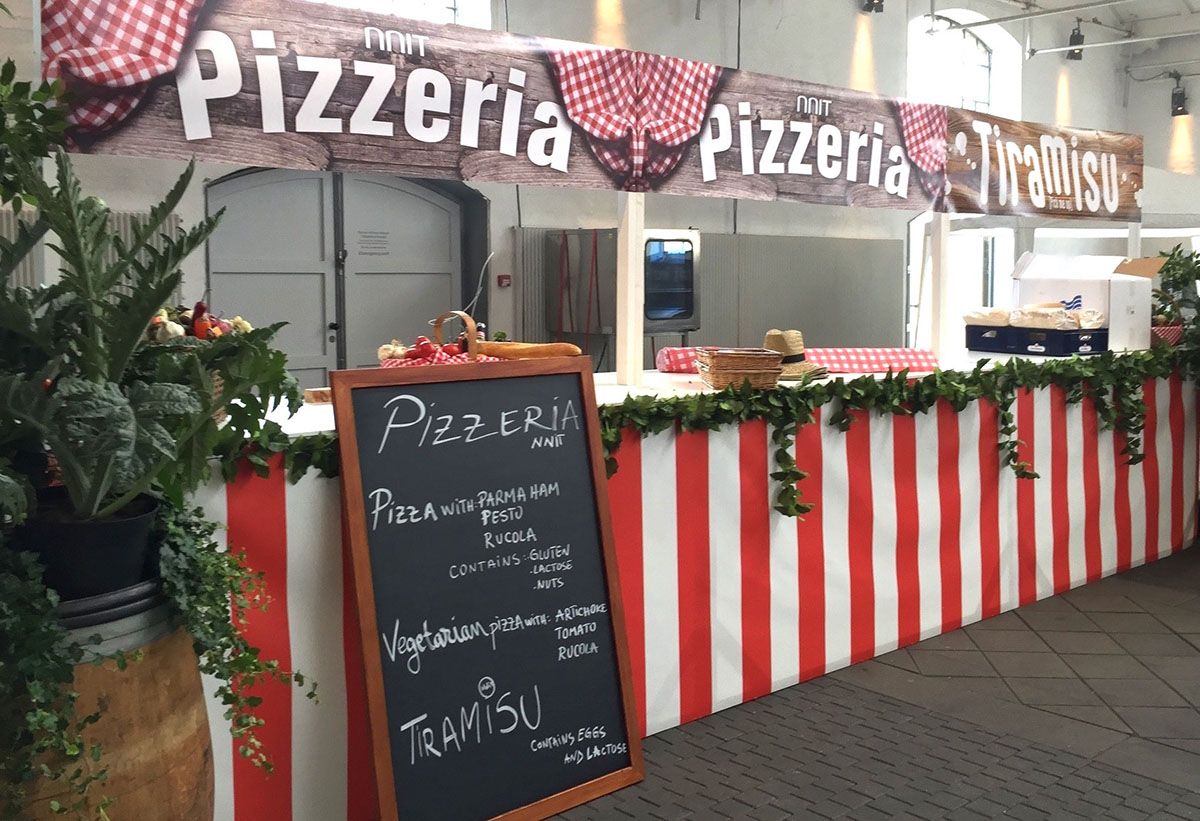 En italiensk pizzabod er dekoreret med rød og hvide farver, et menukort og et pizzeria skilt 