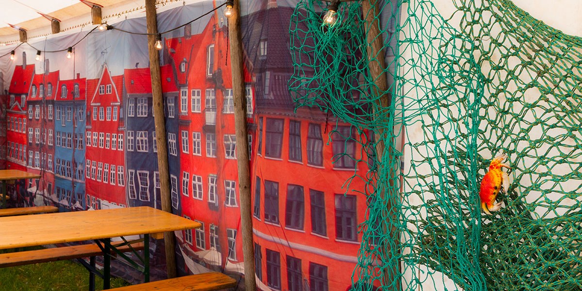 Ved bordene hænger bannere med billeder af husene i Nyhavn 
