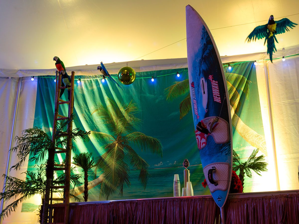 Baren til mexicansk temafest er pyntet med et banner af en tropisk strand, palmer, et surfboard og en papegøje 