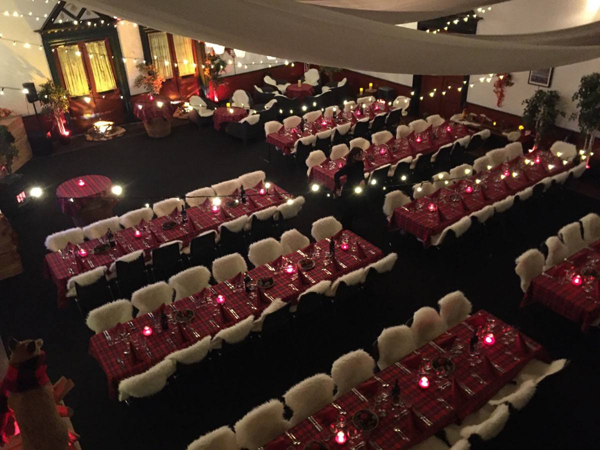 Her er skovmands temafesten set oppefra med røde duge på bordene og skind på stolene  