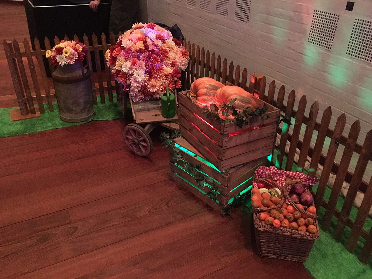 Kasser med blomster, frugt og grøntsager står langs et stakit i lokalet