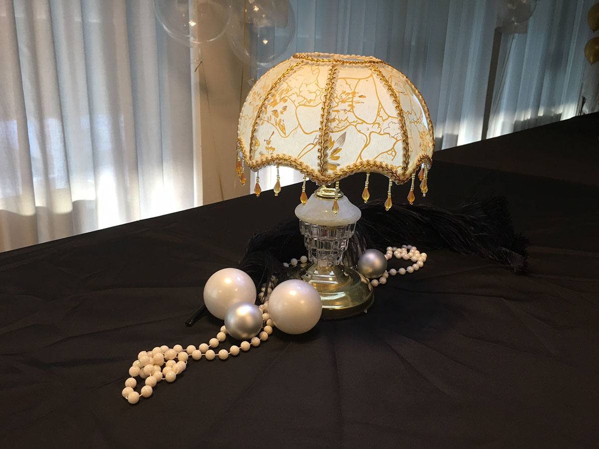 På buffeten står en gammel lampe og ved siden af ligger der perler og perlekæder