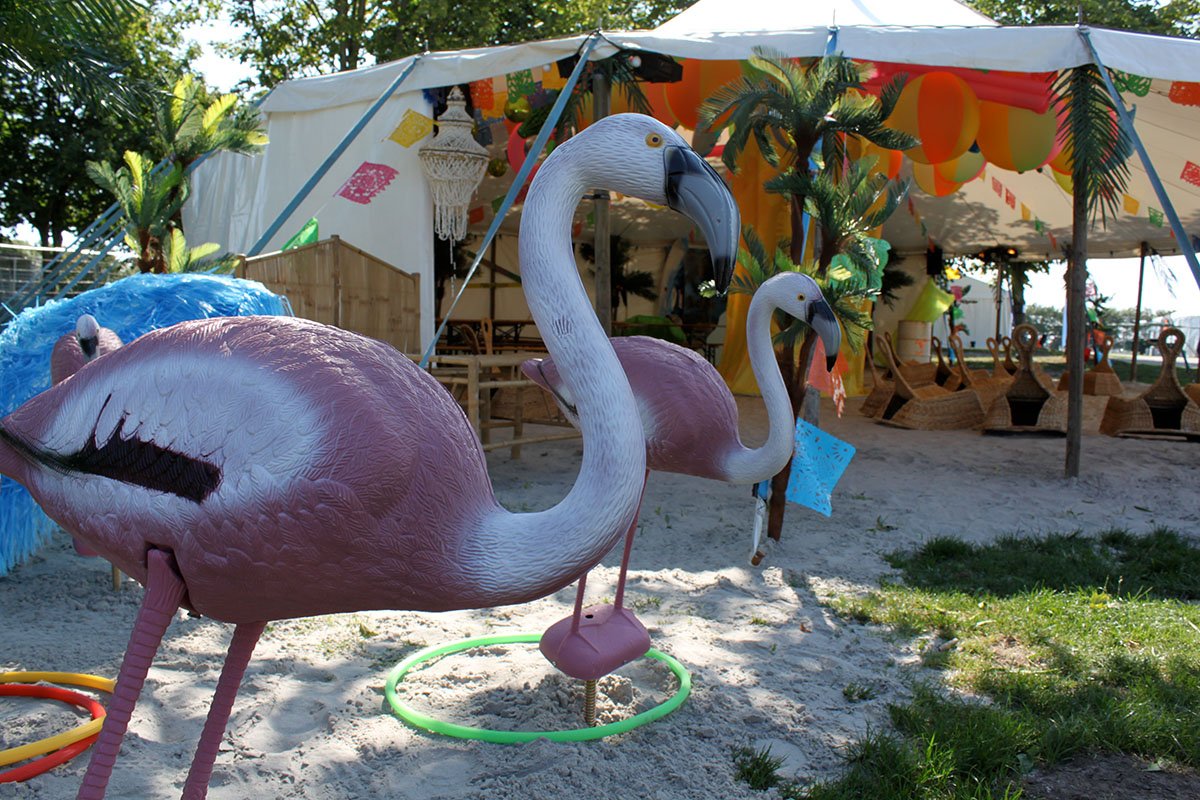 Store plastik flamingoer står i sandet 
