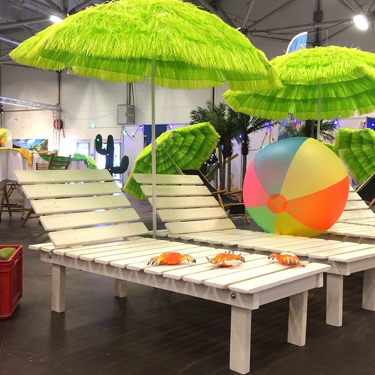 Liggestole, parasoller, badebolde, krabber og en kasse med eksotisk frugt er brugt som dekoration til denne beach party 