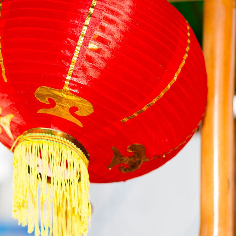 De røde, kinesiske lamper er dekoreret med guldmønster og gule frynser