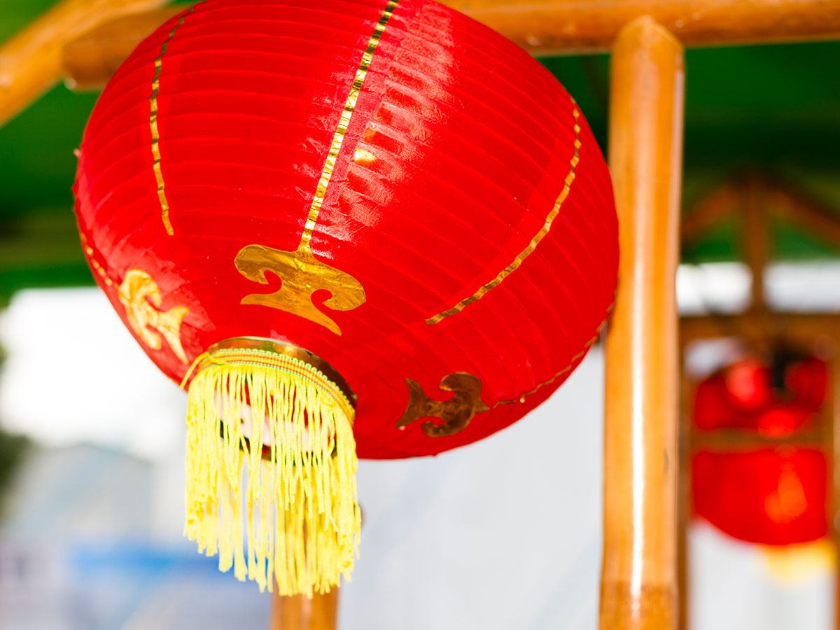 De røde, kinesiske lamper er dekoreret med guldmønster og gule frynser