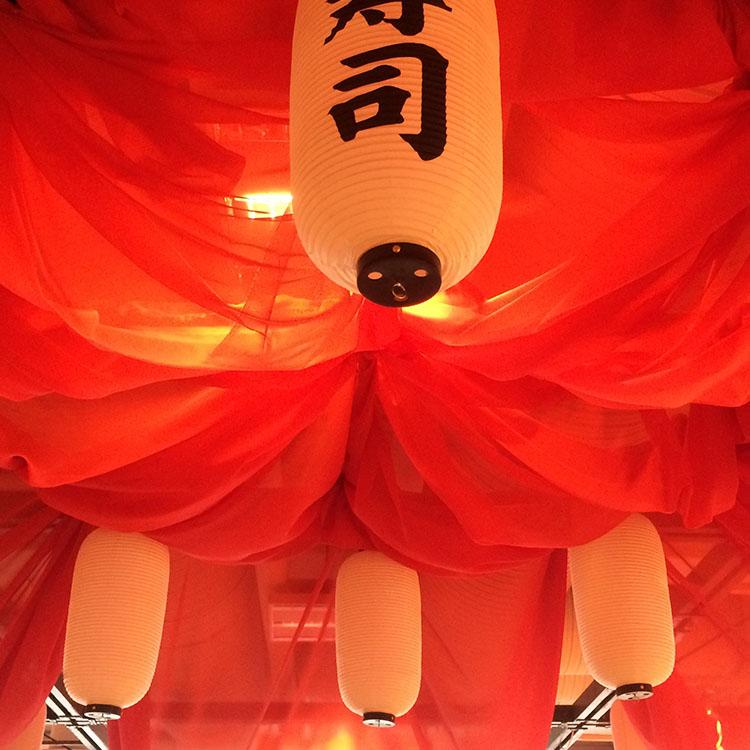 I loftet hænger rødt stof og rispapirslamper med asiatiske skrifttegn