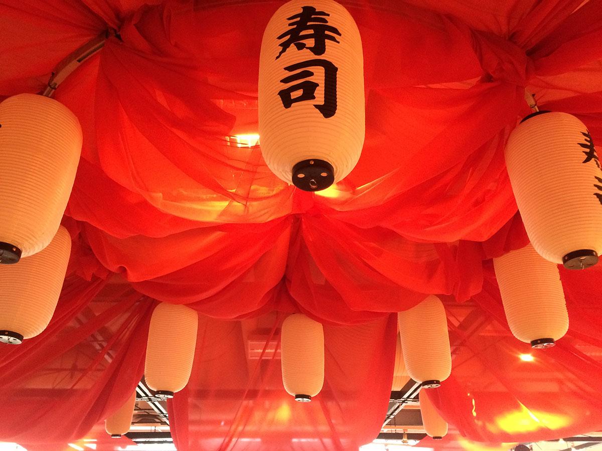 I loftet hænger rødt stof og rispapirslamper med asiatiske skrifttegn