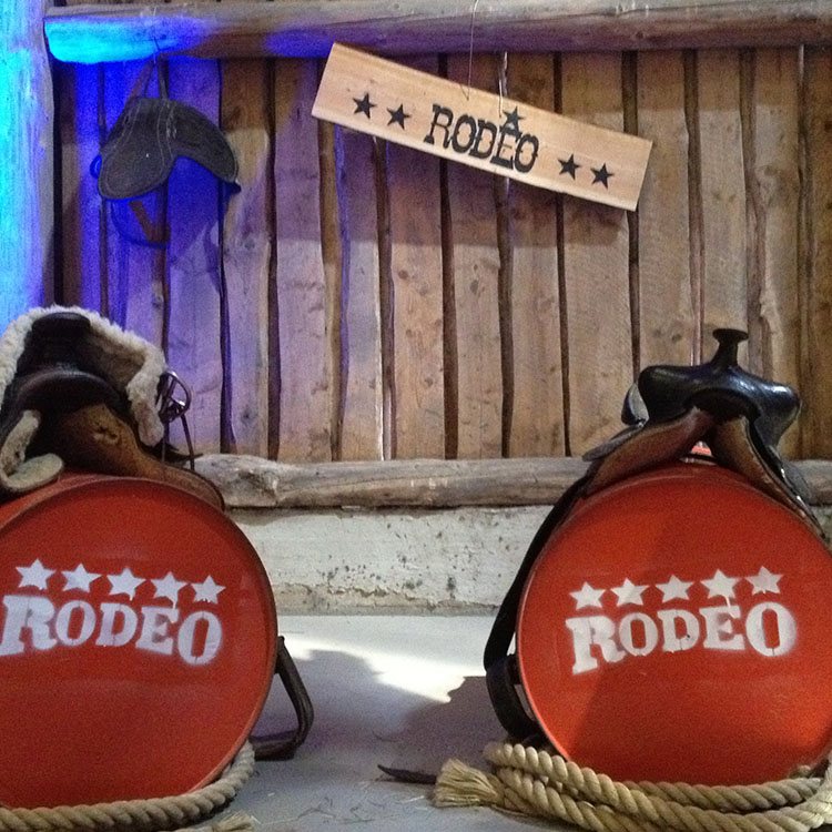 Til denne Rodeo fest er der opsat olietønder med hestesadler over, der er reb og en træbeklædt væg 